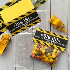 two bags of candy sitting on top of a white wooden table next to construction equipment