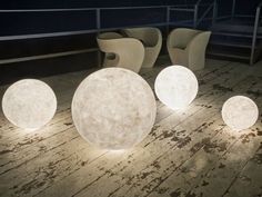 several white balls sitting on top of a wooden floor next to chairs and tables at night