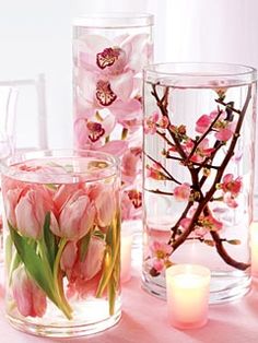 several vases with flowers and candles on a table