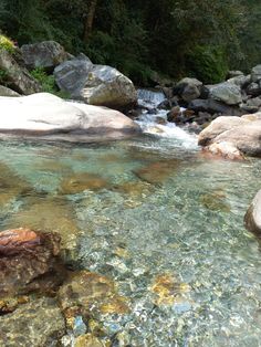 the water is crystal clear and there are rocks on the side of the stream that runs through it