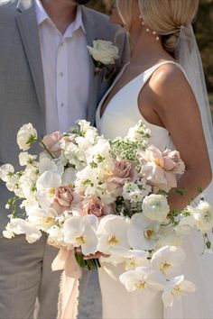 the bride and groom are posing for a photo with their wedding bouquet in front of them