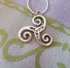 a silver key chain with an ornamental design on it's end, sitting on top of a flowered cloth