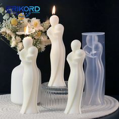 three white figurines sitting on top of a table next to a vase filled with flowers