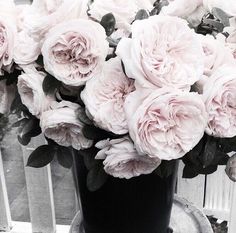 a black vase filled with pink flowers on top of a table