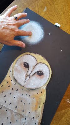 an owl painted on the side of a piece of paper with someone's hand next to it