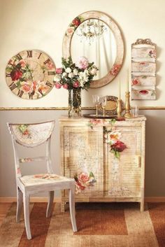 a white chair sitting in front of a dresser next to a mirror and vase with flowers on it