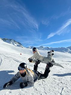 two snowboarders are laying on the ground in the snow