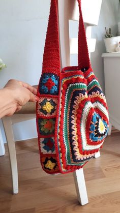 a crocheted purse being held by a woman's hand on a chair