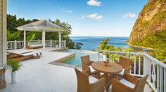 an outdoor patio with chairs, table and gazebo overlooking the ocean