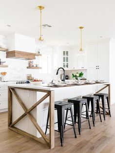 a kitchen with an island and bar stools next to it on a hard wood floor