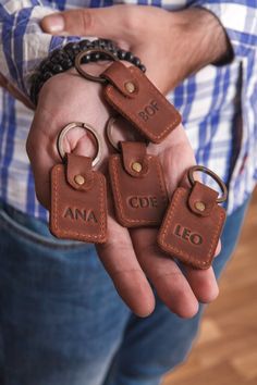 a man is holding four leather keychains in his hands with the word leo engraved on them