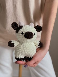 a person holding a small stuffed animal in their left hand and wearing a white shirt