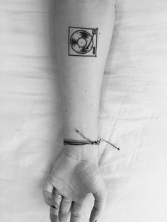 a person's arm with a tattoo on it and a record player in the background