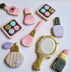 decorated cookies are arranged in the shape of purses and makeup brushes on a table