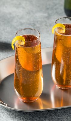 two glasses filled with liquid sitting on top of a metal tray