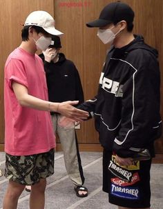 three young men wearing face masks and standing in front of a wooden paneled wall