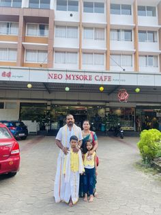 two adults and two children standing in front of a hotel