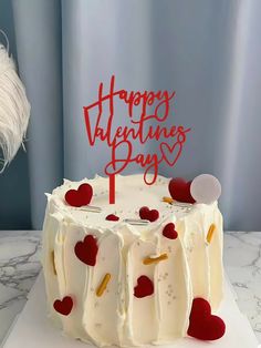 a birthday cake with white frosting and red hearts on the top that says happy valentine's day