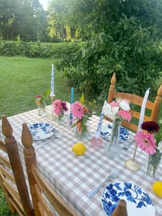 the table is set with plates and flowers in vases on it, along with other place settings