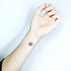 a woman's arm with a small cross tattoo on the left side of her wrist