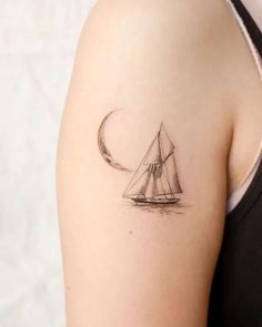 a woman's arm with a small sailboat tattoo on the back of her shoulder