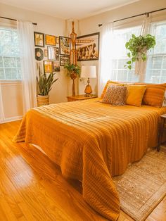 a bed sitting in a bedroom next to a window covered in yellow blankets and pillows