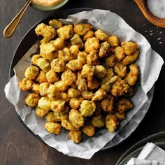 a plate full of tater tots next to some salt and pepper shakers