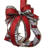 a red and white ribbon wrapped around a christmas ornament on a white background