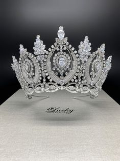 a tiara on display in a box with the word lucky written below it and surrounded by jewels