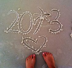 a person standing in the sand with their feet up and writing 2013 written in the sand