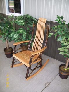 a wooden rocking chair sitting on top of a patio next to a potted plant