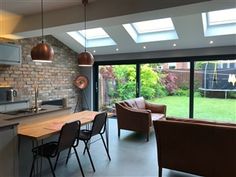 an open kitchen and living room area with large windows on the side of the house