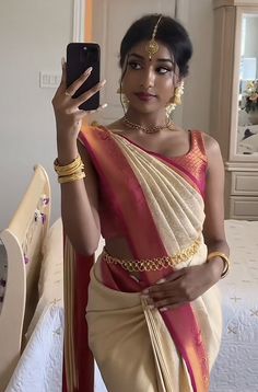 a woman in a sari holding up her cell phone to take a selfie