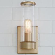 a light that is on the side of a white tile wall with a candle in it