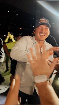 a man with his hand up in the air at a sporting event while other people stand around him