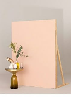 a small table with a vase on it next to a large pink paneled wall