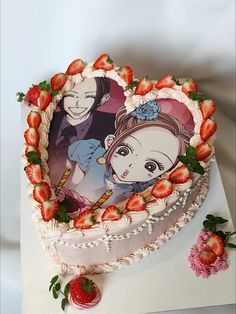 a heart shaped cake with an image of two people on it and strawberries in the foreground