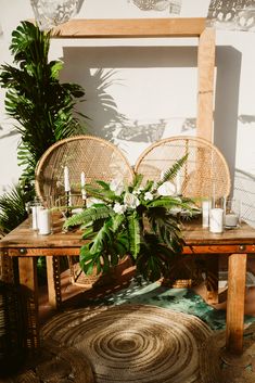 two wicker chairs sitting on top of a wooden table next to a potted plant