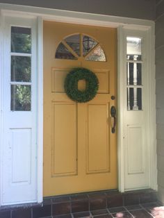 a yellow front door with a wreath on it