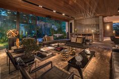 a living room filled with lots of furniture next to large glass windows on top of a wooden ceiling