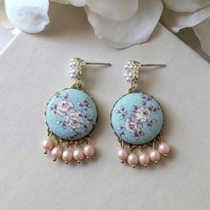 Pretty pastels of aqua blue and peach make a perfect combination in these handmade earrings. For those that love a vintage style, these are handmade with vintage floral fabric, matte peach glass pearls, and unique mini faux pearl posts.  Details: Full length - 1 5/8" (4.1 cm) Width - 3/4" (1.9 cm)   Similar jewelry: Check out my shop for many more floral and vintage styles! Questions? Feel free to send me a message for custom requests, shipping details, and more. At The Whirlwind, each piece of jewelry is thoughtfully crafted one at a time in my home studio. This guarantees that you will receive something genuinely handmade and unique, with meticulous attention to detail devoted to every order from start to finish. Handmade Blue Drop Bridal Earrings, Pastel Drop Earrings Jewelry As Gift, Handmade Blue Bridal Drop Earrings, Pastel Drop Earrings For Gifts, Handmade Pink Clip-on Earrings For Wedding, Pink Handmade Clip-on Earrings For Wedding, Handmade Pastel Dangle Earrings, Cute Handmade Light Blue Earrings, Handmade Light Blue Wedding Earrings