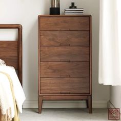 a wooden dresser sitting next to a bed in a room with white walls and flooring