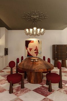 a dining room with red chairs and a wooden table in the center surrounded by paintings