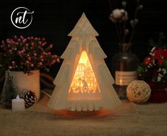 a small white christmas tree sitting on top of a table next to some flowers and candles