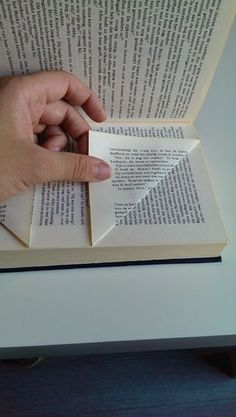 a person is holding an open book and pointing at it