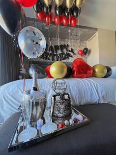 a birthday cake and balloons are on a tray in the middle of a bed room