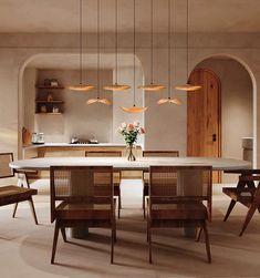 a dining room table with chairs and lights hanging from the ceiling