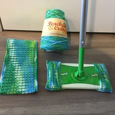 a green mop sitting on top of a wooden floor next to two cleaning products