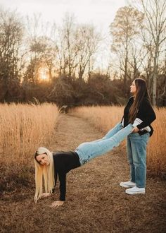 two women are standing in the middle of a field and one is doing a handstand