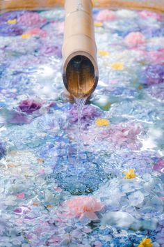 a pipe pouring water into a bucket filled with flowers